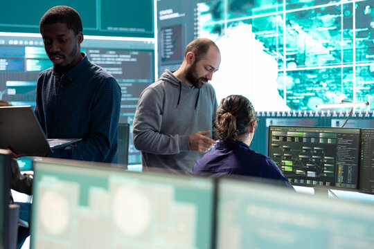 Governmental hackers working on computer network in high tech office, focusing on data security and cyber operations. Cybercrime, data protection and threat detection in secure environment.