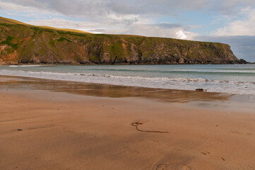 A beach with a rocky cliff in the background