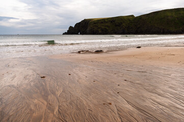 A beach with a rocky cliff in the background