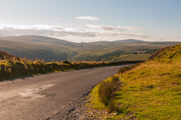 A road with a grassy hillside in the background