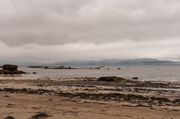 Fototapeta premium A beach with a cloudy sky and rocks in the foreground