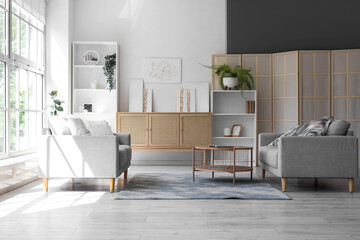 Interior of stylish living room with sofas, drawers and paintings