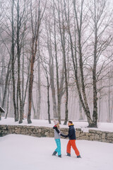 Guy and girl are standing in a winter park, holding hands and looking at each other