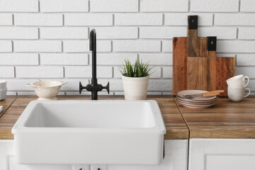 Wooden counter with ceramic sink and dishes in kitchen. Closeup