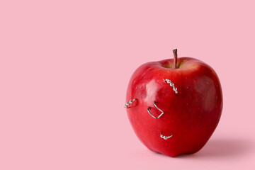 Apple with piercing on pink background