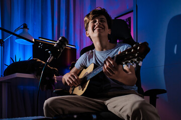Young musician enjoying playing guitar in a creative bedroom