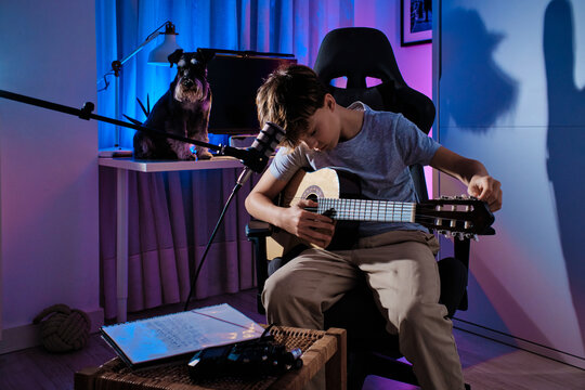 Young musician playing guitar in colorful room ambiance