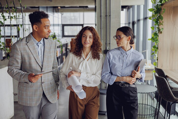 A diverse team of professionals actively discusses exciting ideas in a modern, contemporary office...