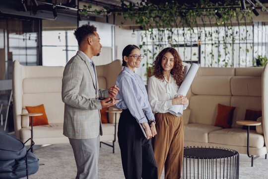Three professionals discuss project plans in a stylish workspace that fosters collaboration and creativity