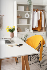 Laptop and vase with spring flowers on desk in home office