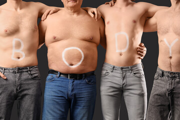 Naklejka premium Group of men with word BODY on their skin against black background. Body positive concept