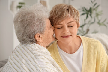 Senior woman kissing her daughter at home, closeup. Mother's Day celebration