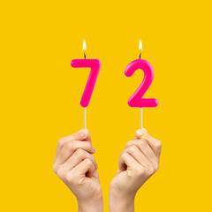 Birthday number 72 - Hands holding fuchsia colored candles