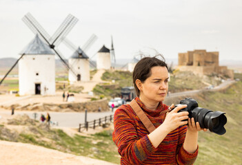 Young woman tourist with a camera Consuegra, who came to the Mota del cuervo, photographs the...