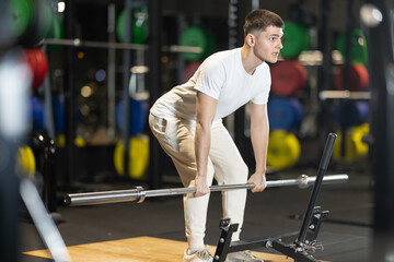 Young man executing conventional deadlift with proper stance and grip, targeting posterior chain...