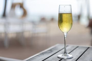Sparkling beverage served in a tall glass on a wooden table by the seaside during a sunny day