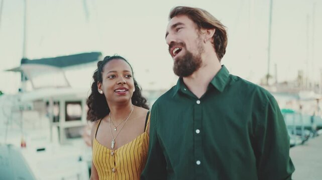 Close up Interracial couple. Close-up of a cute woman and man walking and talking in the port background yachts