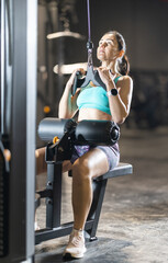 Fit woman performing close-grip lat pulldown on cable machine at gym, engaging lats and biceps with controlled movement during upper body strength training