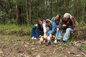 Family petting dog while resting during hike in forest