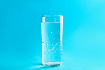 Soda water in glass on light blue background