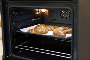 Freshly baked croissants on baking sheet in oven