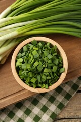 Fresh green onions on wooden table, top view