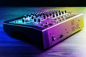 Professional DJ mixer on wooden table in bright lights, closeup