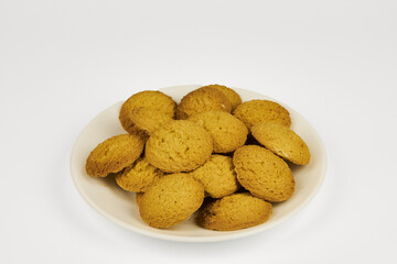 A plate of cookies is sitting on a white background. The cookies are small and round, and they are all the same color. The plate is empty, and the cookies are arranged in a neat pile