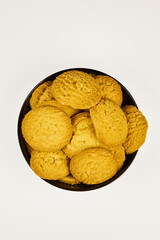 A plate of cookies sits on a white background. The cookies are small and round, and all the same color. The plate is black, and the cookies are arranged in a pyramid shape, one on top of the other.