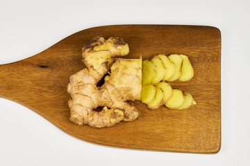 Ginger root in close-up on a wooden board with slices cut into slices for preparing an infusion for a cold.