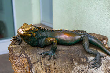 Bronze iguana sculpture on wooden trunk