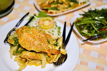 Thai dishes of yellow curry crab, stir-fried morning glory (Kang Kong) and red curry chicken at Cliff Restaurant, Patok Bay, with a night view of the sea in the background - Ko Racha