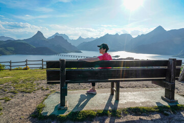 woman smiling by the bench contemplating the lake and the mountains of Riaño