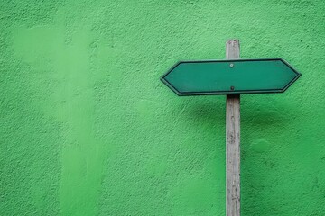 A green directional sign set against a vibrant green wall