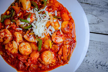 Tasty seafood pasta with spicy tomato sauce and clams topped with cheese and peppers.