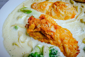 Italian chicken pasta in white plate served with heavy cream and vegetables.