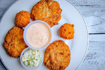 top view of fried crab cake with white sauce and salad served in a white plate.