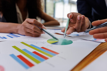 Group of confident business people point to graphs and charts to analyze market data, balance sheet, account, net profit to plan new sales strategies to increase production capacity.	