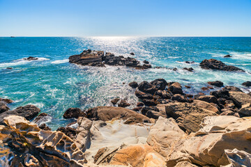 Coastal cliffs along California's Highway 1 in Northern California. Rugged ocean rocks, crashing waves, and a colorful sky create a breathtaking Pacific Coast landscape