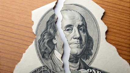 Torn dollar bill revealing Benjamin Franklin's face.