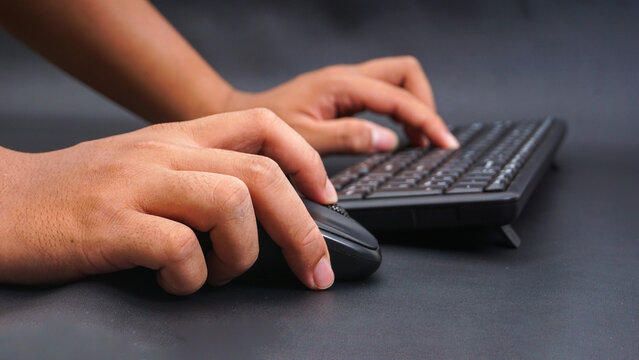 Man hand typing on computer keyboard and holding computer mouse isolated on black background