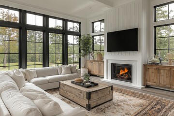 Obraz premium Modern white farmhouse living room with black windows, neutral palette, wooden accents, large couch, TV, fireplace, and small indoor tree.