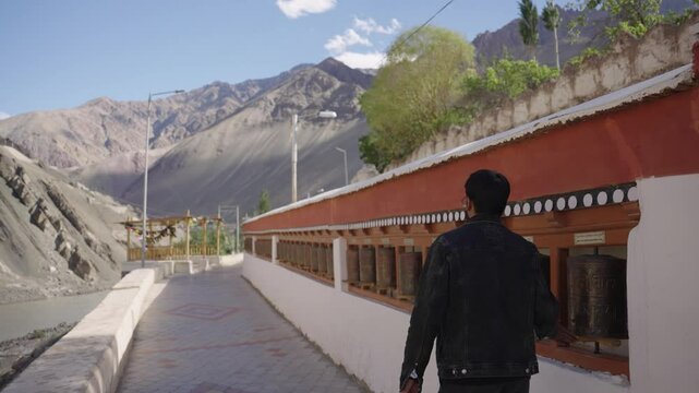 4K footage of a man walking past aged monastery walls decorated with centuries-old frescoes and religious symbols.