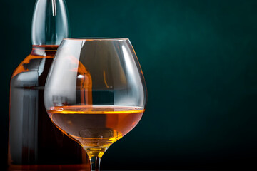 French cognac V.S.O.P. in snifter glass with bottle on dark green background