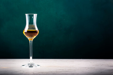 Italian grape vodka grappa in a glass on a dark green background