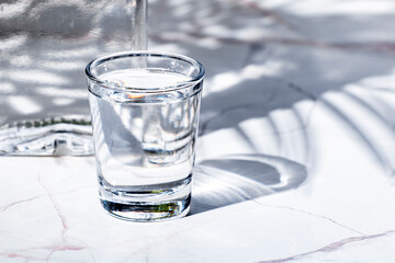 Vodka in glass and bottles of strong drink on white background, hard light