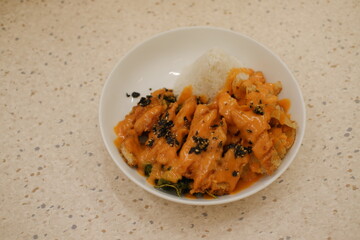 a delicious bowl of food featuring crispy fried chicken cutlets drizzled generously with a creamy orange sauce