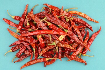 A pile of dried red chili peppers on a blue background.