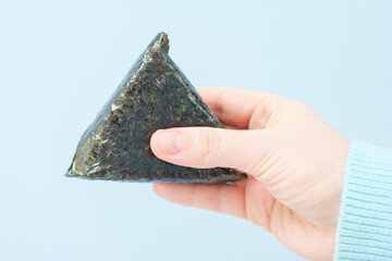 Female hand holding korean samgak close-up on gray background. © TATIANA KIM