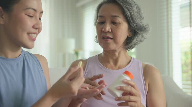 Young adult child give advice to middle age old mum. Love health care older aged mom asia elder people at home happy family help protect aging asian life. Vitamin d c e k zinc omega 3 fish oil pill.